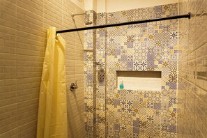 A bathroom with a shower curtain, a towel rack, and a wall with patterned tiles.