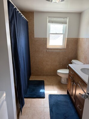 A bathroom with a shower curtain, a window, a toilet, and a sink. - 3 Bedroom Escape, Walk to Beach - 5 Min to city (Pembroke)
