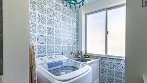 Une salle de bain avec une grande fenêtre, un lave-linge et des carreaux décorés.