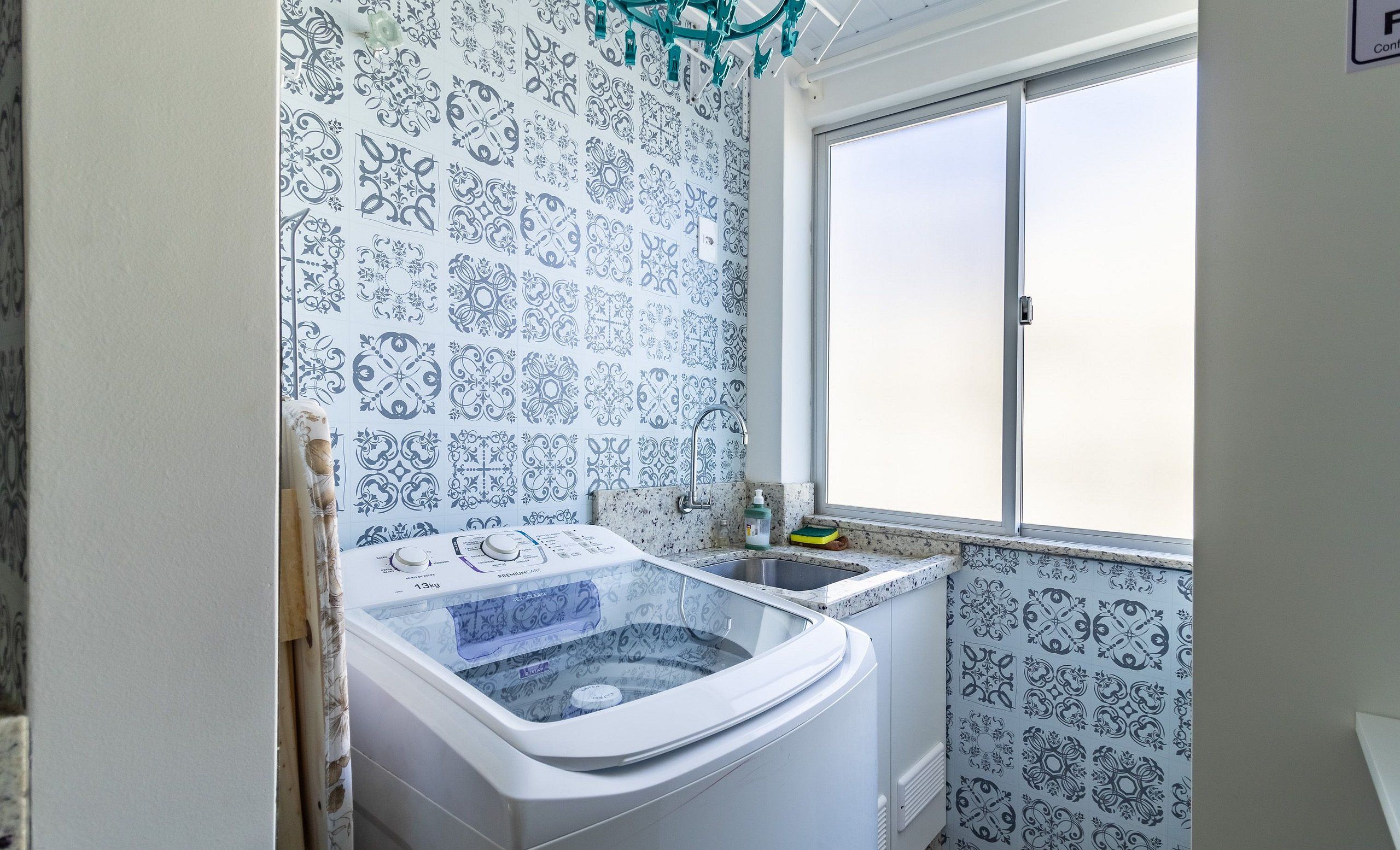 A bathroom with a large window, a washing machine, and patterned tiles.