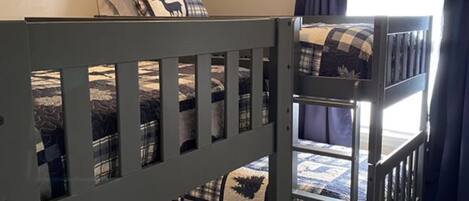 A bunk bed room with a window, curtains, and a ceiling light.