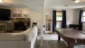 A living room with a fireplace, a pool table, and a sofa.