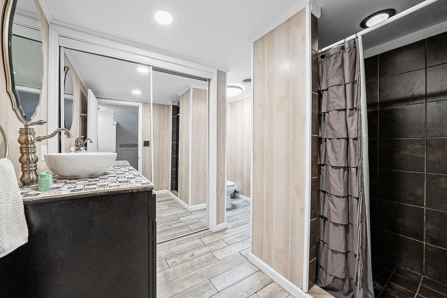 A bathroom with a large mirror, a sink, and a shower area.
