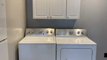 A laundry area with a washer and dryer, a white refrigerator, and a set of cabinets above the appliances.