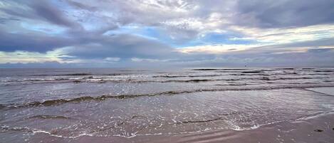 A beach with waves and a cloudy sky.