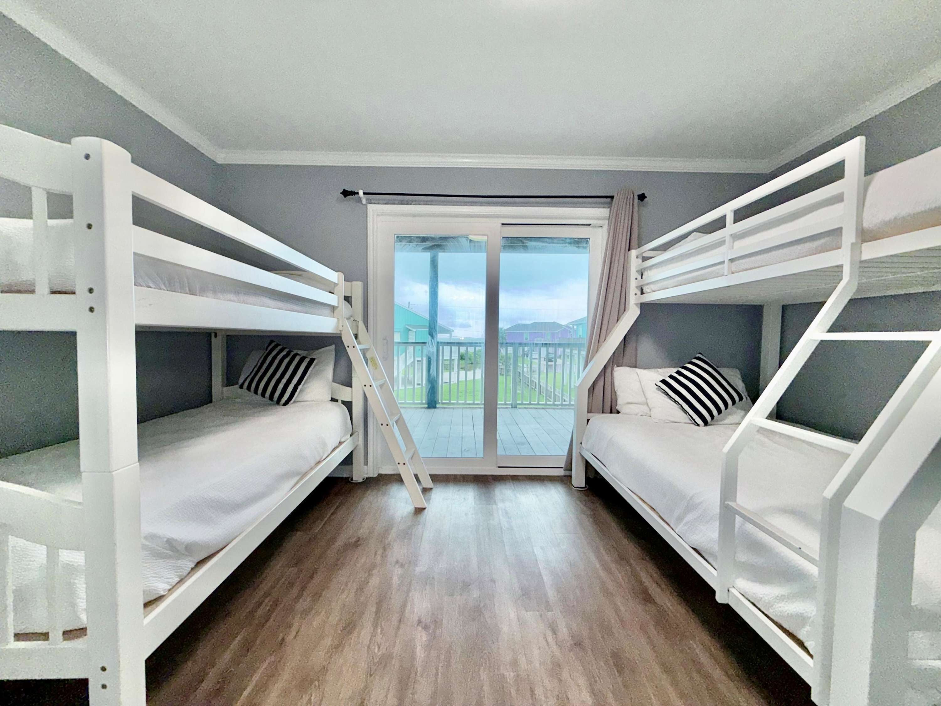 Una habitación con dos literas, una puerta corrediza de vidrio que da a un balcón y piso de madera.