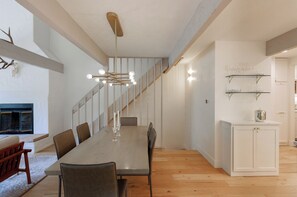 Una sala da pranzo moderna con un lungo tavolo, sedie, un lampadario e una scala che conduce a un altro piano.