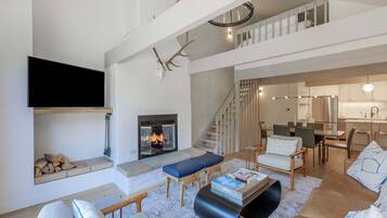 Un salon moderne doté d’une cheminée, d’un coin salon et d’un escalier menant à un niveau supérieur.