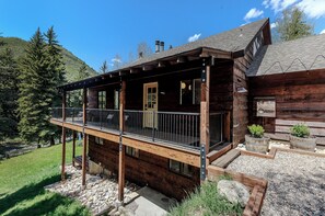 A wooden cabin with a balcony, a door, and a window. - 3BR West Vail duplex with river views, hot tub, fireplace, and deck. (Vail)