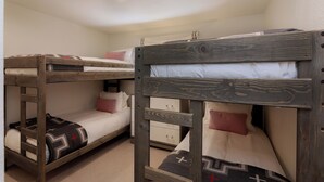 A bunk bed room with a wooden headboard and a lower bunk with a patterned pillow. - 3BR West Vail duplex with river views, hot tub, fireplace, and deck. (Vail)