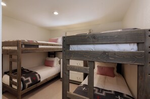 A bunk bed room with a wooden headboard and a lower bunk with a patterned pillow. - 3BR West Vail duplex with river views, hot tub, fireplace, and deck. (Vail)