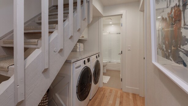 A laundry room with a washing machine and dryer, a staircase with white railings, and a bathroom with a shower and toilet. - 3BR West Vail duplex with river views, hot tub, fireplace, and deck. (Vail)