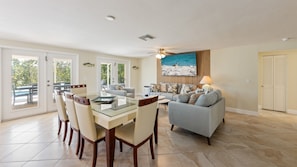 A spacious living area with a dining table, chairs, a sofa, and a television mounted on the wall. - Beach meets Bay: Your Private Poolside Beach-Boat-Bay-Paradise (Anna Maria)