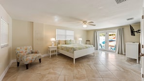 A bedroom with a bed, a chair, a ceiling fan, and a view of the outdoors. - Beach meets Bay: Your Private Poolside Beach-Boat-Bay-Paradise (Anna Maria)