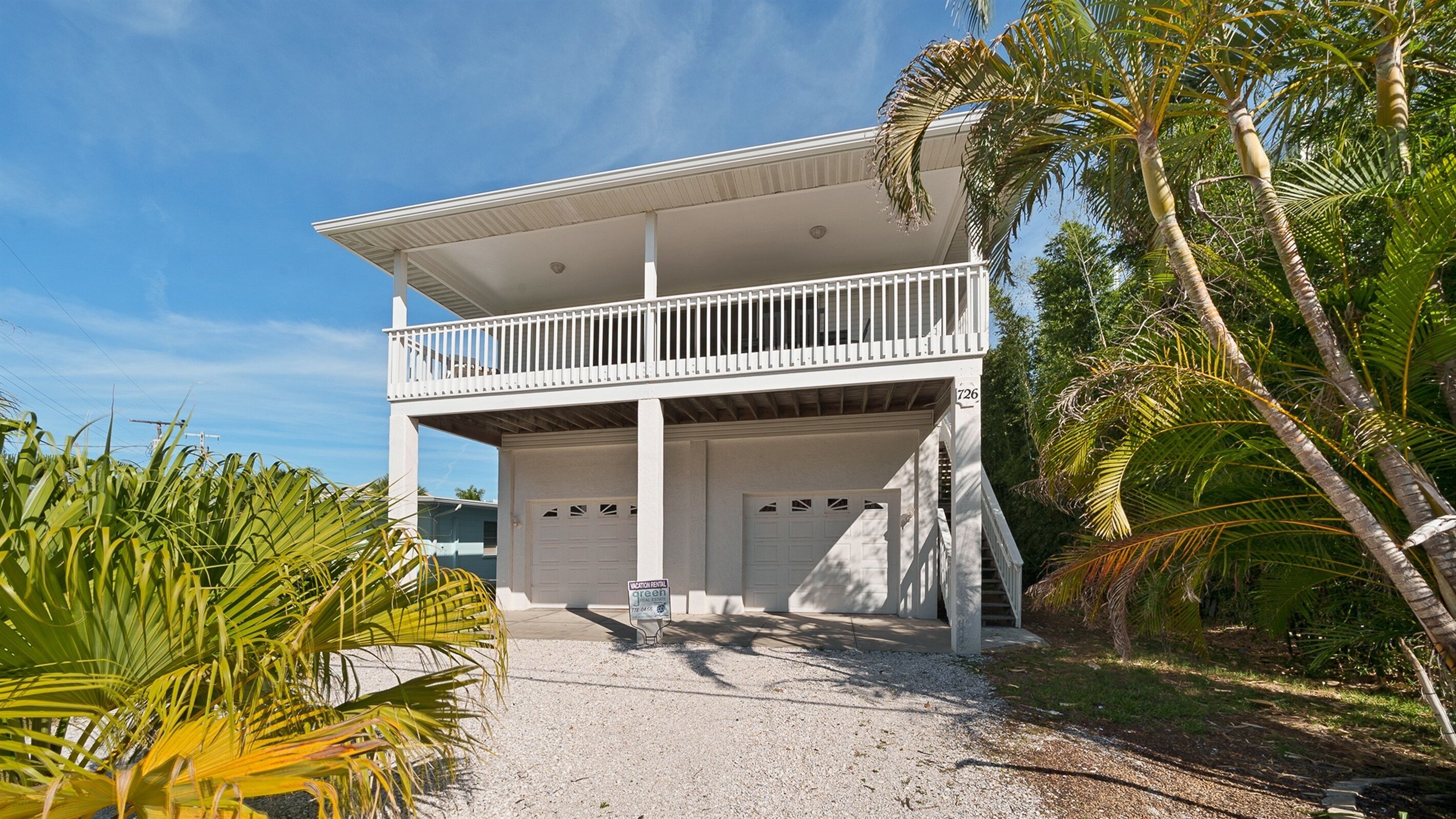 A two-story building with a balcony, a garage, and a driveway.