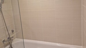 A bathroom with a bathtub, a shower, and a glass-enclosed shower area. - Room-a Friendly Budget Room That Deliver (Southampton)