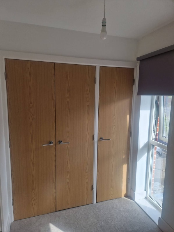 A room with a large wardrobe, a window with a view, and a hanging light fixture.