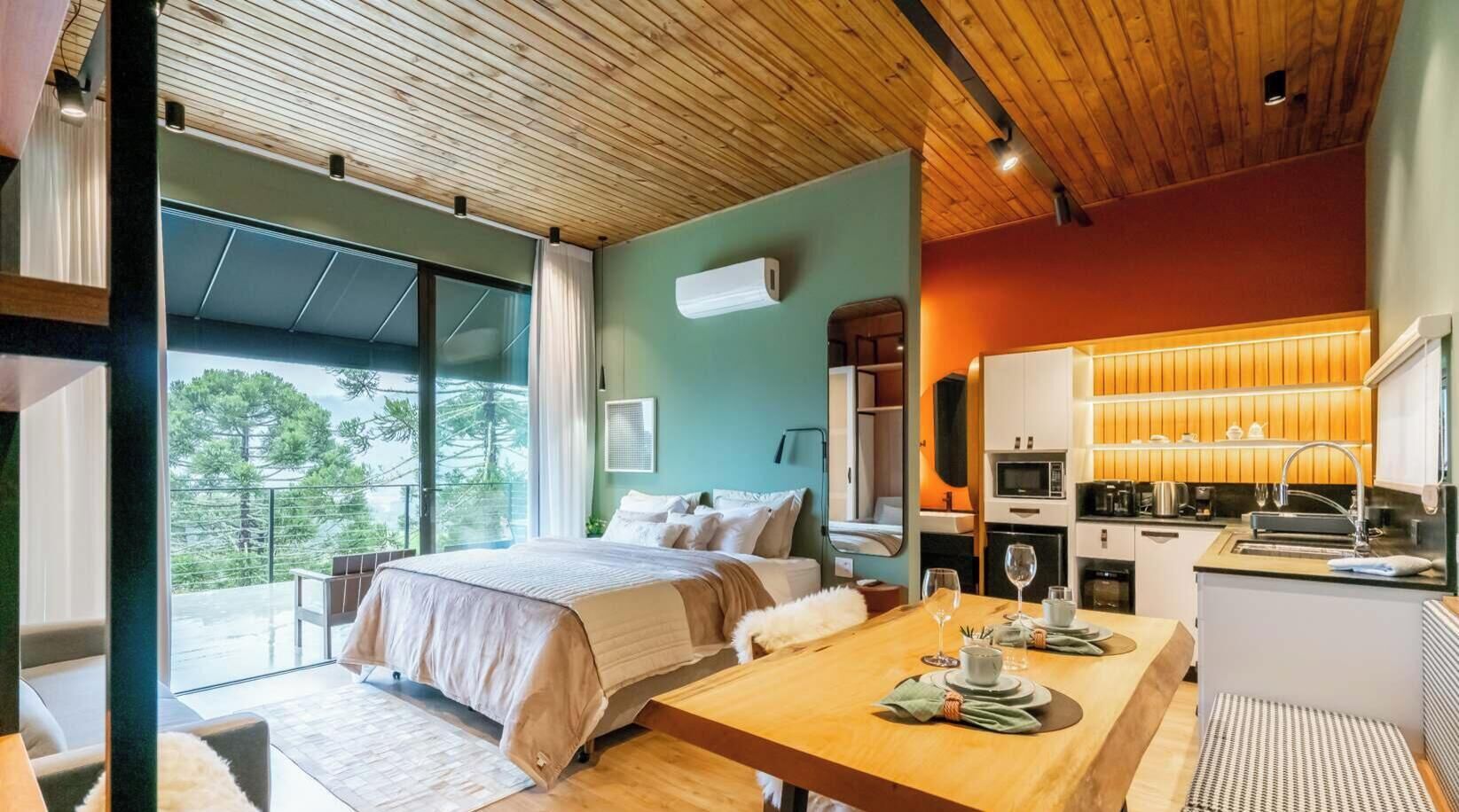 A modern bedroom with a large bed, a dining table, and a kitchen area.