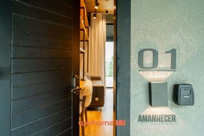 A hotel entrance with a dark wooden door, a pet-friendly area with a dog, and a wall-mounted intercom labeled '01 AMAHNECER'.