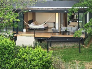 A modern house with a hammock, outdoor seating, and a garden.