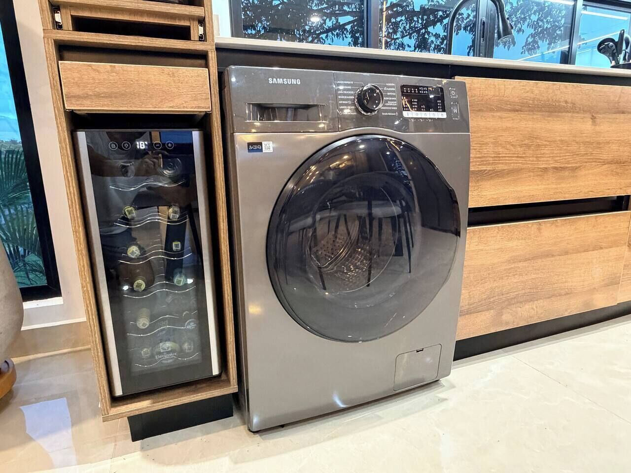 Eine Samsung Waschmaschine in einer modernen Küche mit Holzausstattung und einem eingebauten Backofen.
