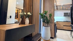 Et moderne interiør med et træspisestueområde, en stor potteplante og et køkken i baggrunden.
