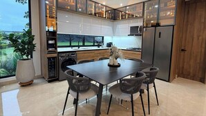 Een moderne keuken met een eethoek, inbouwmeubels en een groot raam met uitzicht op groen.