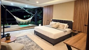Een moderne slaapkamer met een groot bed, een houten nachtkastje, een kleine tafel en een hangmat voor het raam.