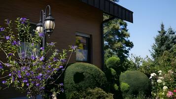 A modern building with a well-maintained garden, including neatly trimmed bushes and flowering plants.