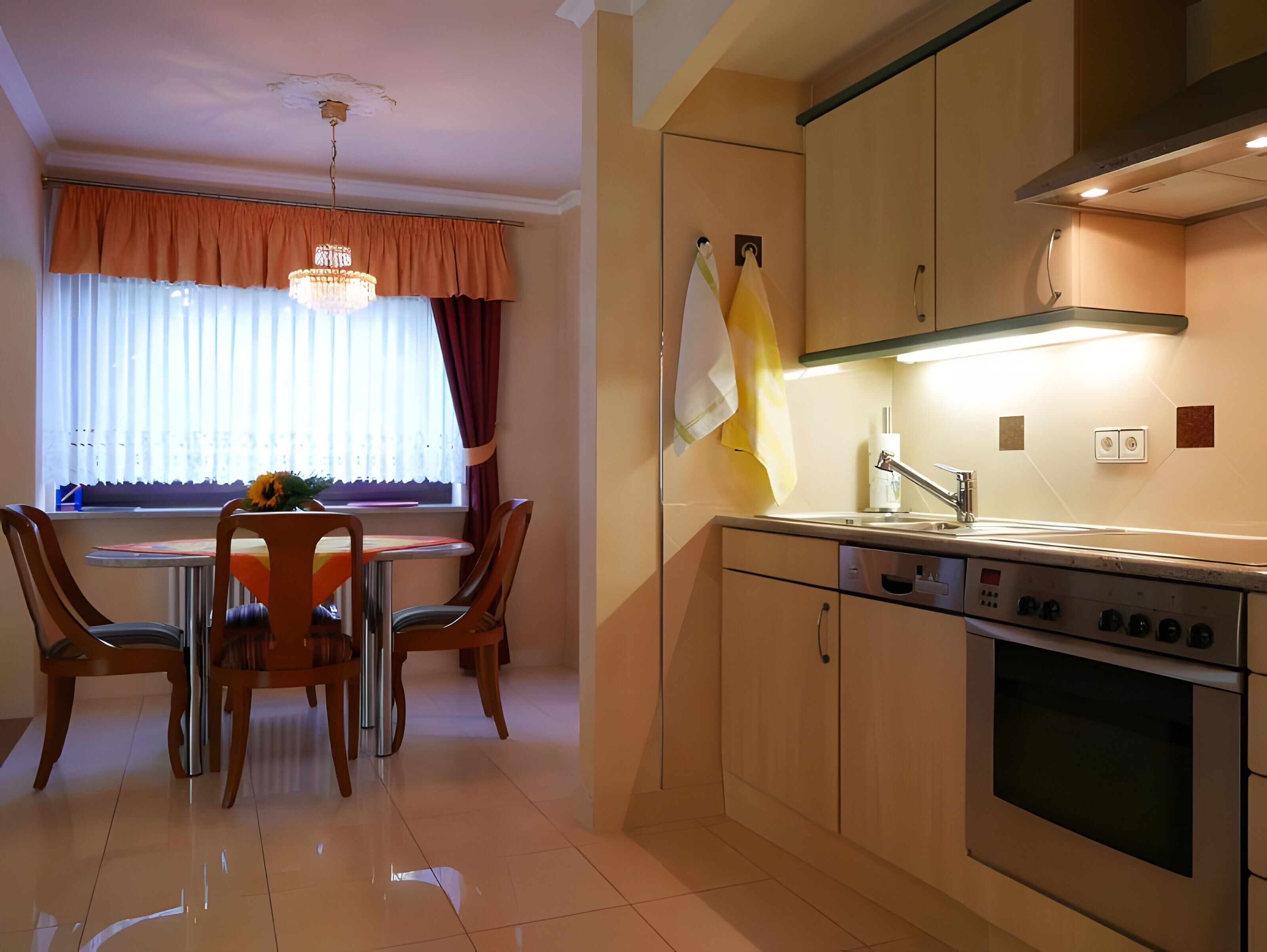 Una cocina moderna con comedor, electrodomésticos de acero inoxidable y una lámpara de araña.
