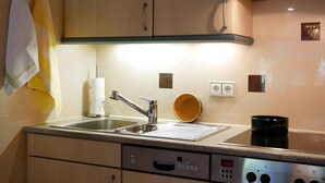 Ett modernt kök med en diskho i rostfritt stål, en inbyggd ugn och en mikrovågsugn.