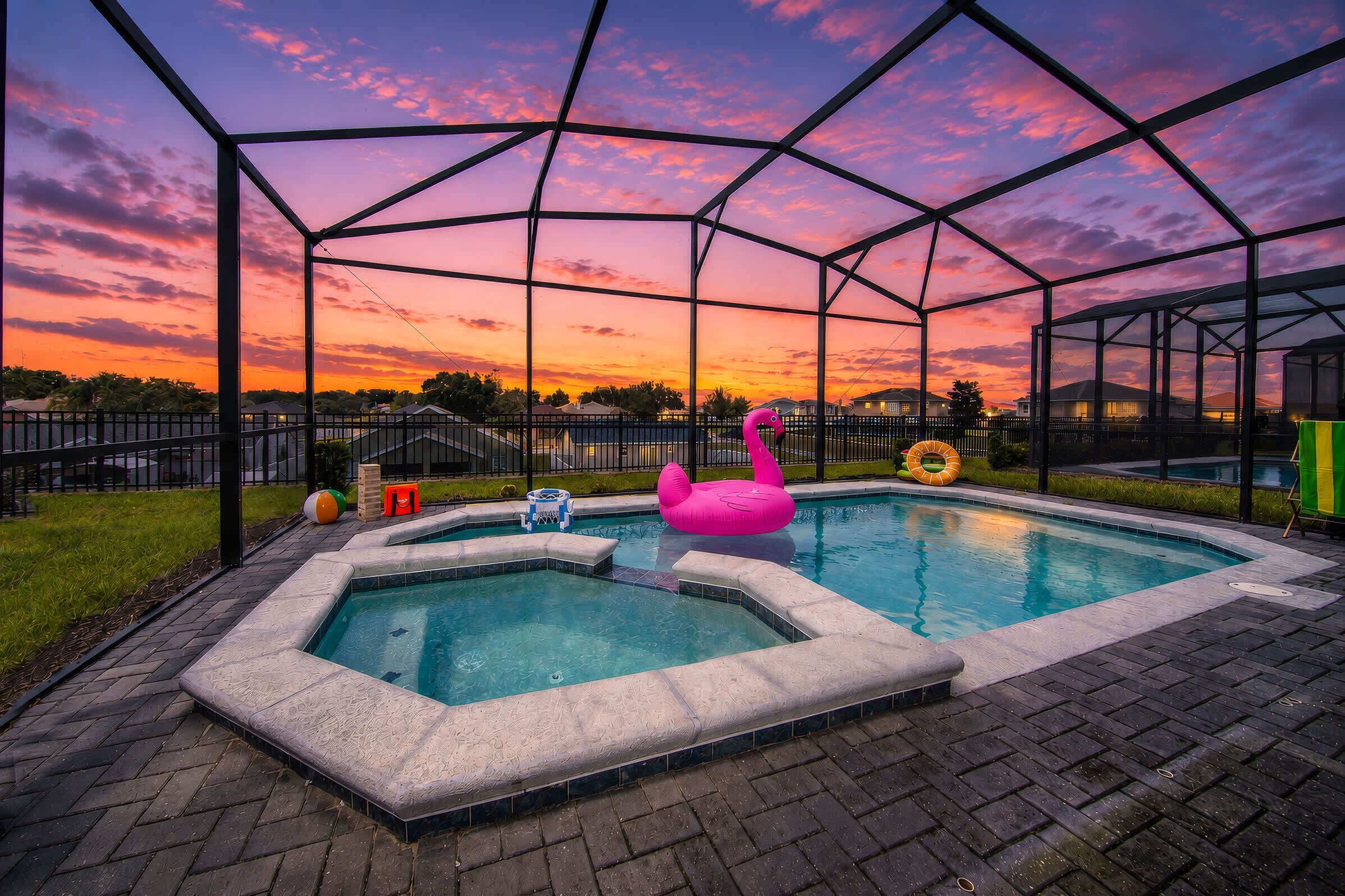 A swimming pool with a glass enclosure, surrounded by a brick patio.