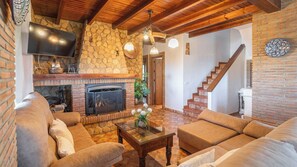 Ein gemütliches Wohnzimmer mit Kamin, Treppe und Flachbildfernseher.