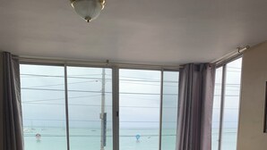 Ett sovrum med en säng, ett fönster och utsikt över havet.