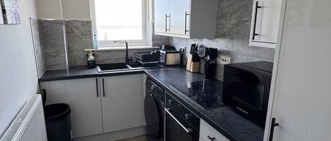 Una cocina compacta con horno empotrado, microondas y ventana que proporciona luz natural.