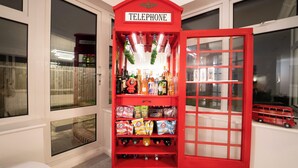 A red telephone booth with a sign, shelves with snacks, and a toy bus. - Stunning Sea View Flat on The Leas Panoramic Estuary Sunsets, Steps to Beach (Sheerness)