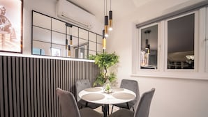 A dining area with a round table, four chairs, a potted plant, and pendant lighting. - Stunning Sea View Flat on The Leas Panoramic Estuary Sunsets, Steps to Beach (Sheerness)