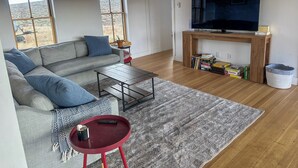 En stue med sofa, sofabord, tv og pejs.