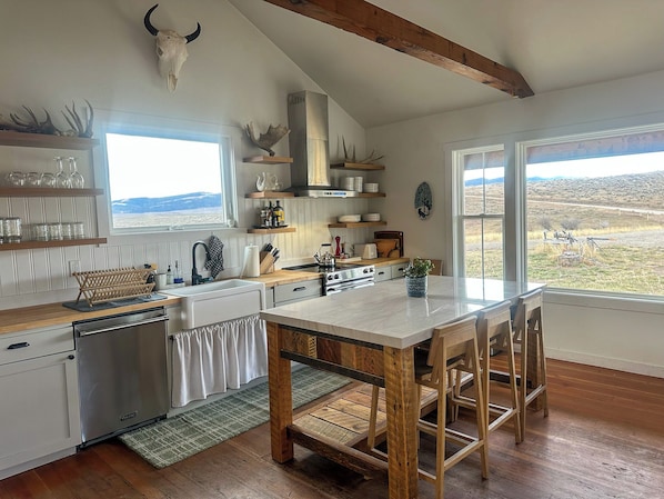 Una cocina con una isla grande, vigas de madera y vistas al exterior.