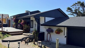 Ein Wohnhaus mit Garage und einer Veranda, die mit Blumentöpfen geschmückt ist, unter einem wolkenlosen Himmel.