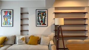 A modern living room with a sofa, a coffee table, and a floor lamp. There are two framed artworks on the wall. - Lovely 3 BDRM Apartment in Napoles, CDMX. (Ciudad de México)