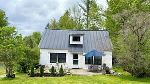 Ein modernes Haus mit grauem Dach, weißem Außenputz und einer Veranda mit Tisch und Stühlen.