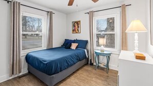A bedroom with a bed, a ceiling fan, a nightstand, a lamp, and a window with blinds. - Entire home in Concord, North Carolina, United States (Concord)