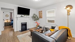 A living room with a fireplace, a sofa, a coffee table, and a television mounted on the wall. - Entire home in Concord, North Carolina, United States (Concord)