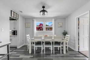 A dining area with a table and chairs, a window with a view, and a ceiling fan.