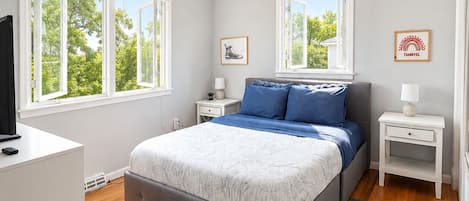 Un dormitorio moderno con una cama grande, dos mesitas de noche, un televisor y una lámpara en el techo.