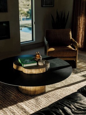 A modern living room with a round coffee table, a book, and a decorative object. - Secluded Retreat | Two Homes, Pool + Firepit (Yucca Valley)