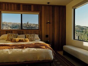 Une chambre avec un grand lit, un banc et une vue sur un paysage désertique.