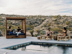 Un espace aménagé au bord de la piscine, avec des sièges en bois et une structure également en bois.