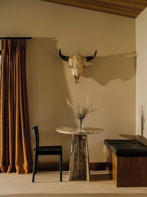 A dining area with a round table, chairs, and a bull skull mounted on the wall. - Secluded Retreat | Two Homes, Pool + Firepit (Yucca Valley)